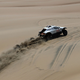 The white Sodicars rally truck driving across a sand dune